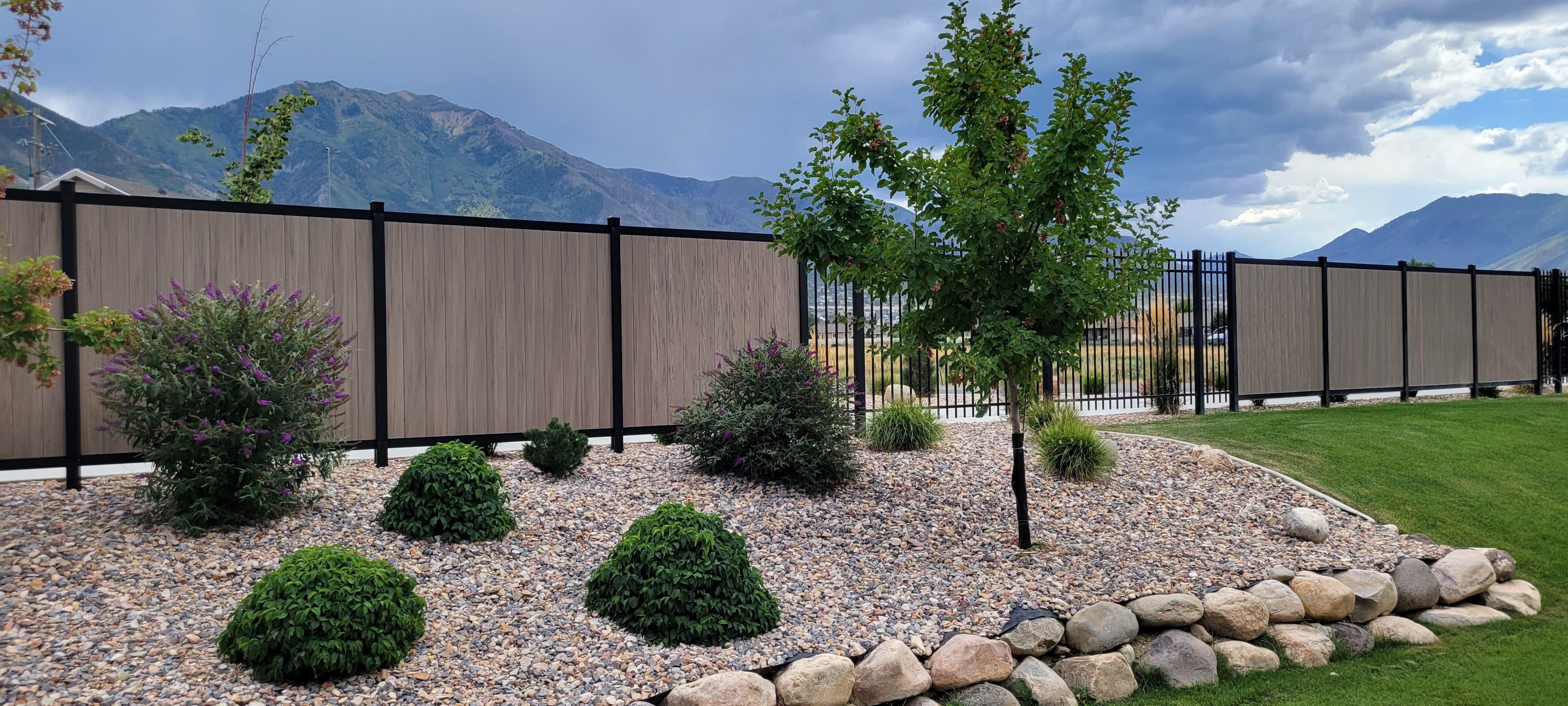Composite privacy fence with rock bed by SG Landscaping